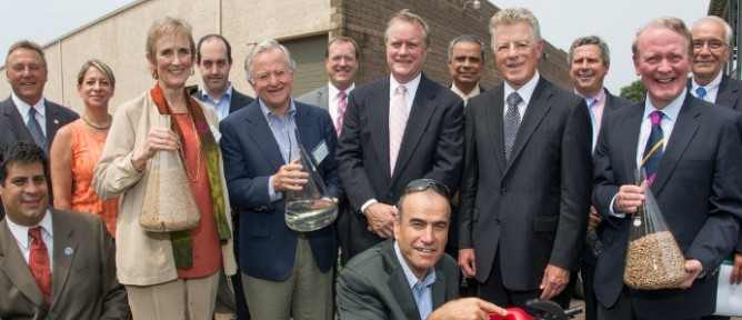 Primus Green Energy Chairman Dr. Yom-Tov Samia (front middle) with guests including former New Jersey Governor Jim Florio at the company's demo plant dedication. The beakers contain wood pellet feedstock and Primus' 93-octane gasoline.